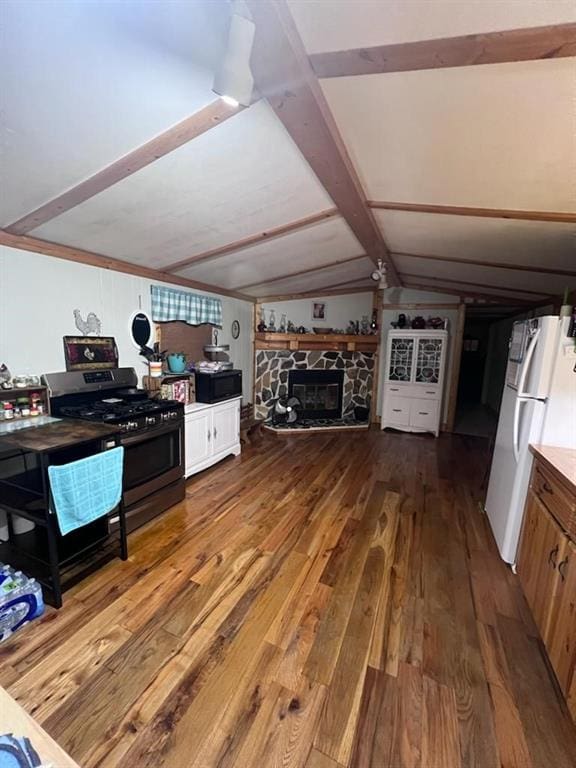 kitchen featuring a fireplace, hardwood / wood-style floors, stainless steel range with gas stovetop, and white fridge