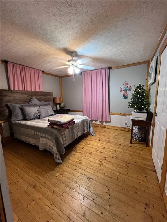 bedroom featuring radiator, light hardwood / wood-style floors, ceiling fan, and a textured ceiling