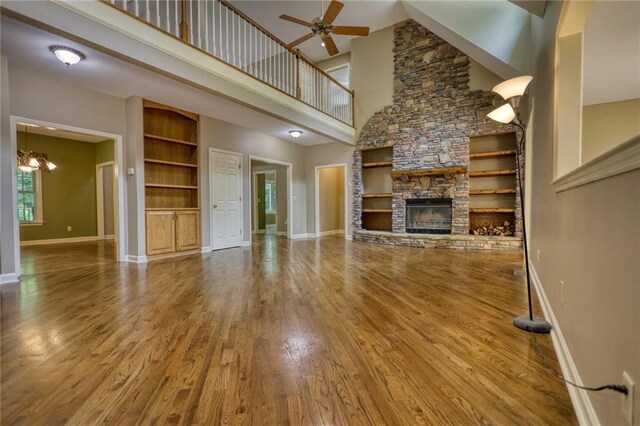 116 Woolsey Creek Trl, Fayetteville, GA 30215 - unfurnished living room featuring a towering ceiling, ceiling fan, wood finished floors, a fireplace, and baseboards