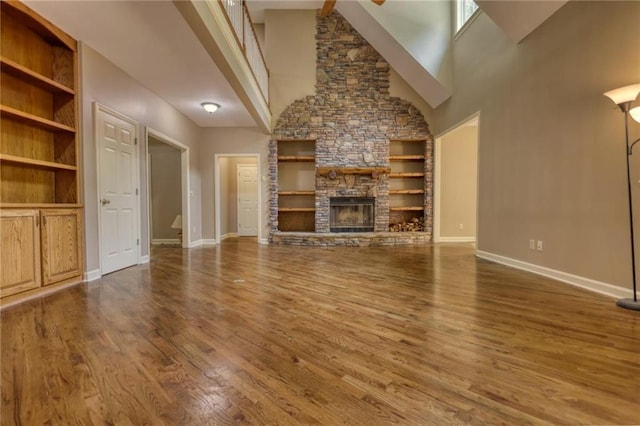 116 Woolsey Creek Trl, Fayetteville, GA 30215 - unfurnished living room featuring built in features, wood finished floors, baseboards, a high ceiling, and a fireplace