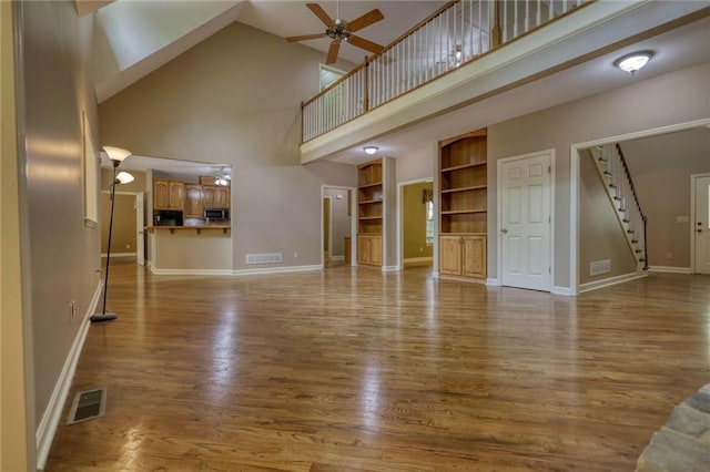 116 Woolsey Creek Trl, Fayetteville, GA 30215 - unfurnished living room featuring a high ceiling, stairs, ceiling fan, wood finished floors, and built in features