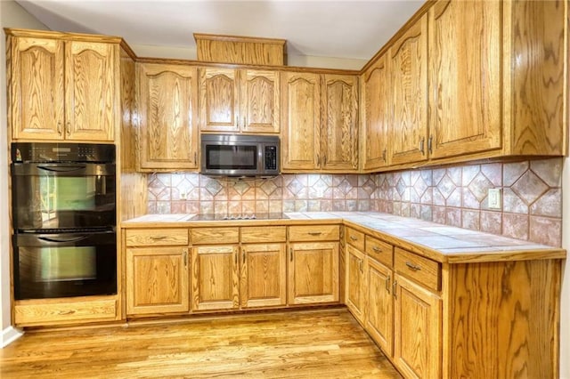 116 Woolsey Creek Trl, Fayetteville, GA 30215 - kitchen featuring black appliances, tile counters, light wood finished floors, and decorative backsplash