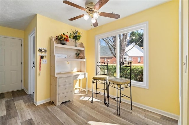 dining area with a ceiling fan, light wood-type flooring, and baseboards