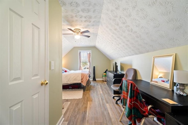 bedroom with baseboards, lofted ceiling, ceiling fan, wood finished floors, and a textured ceiling