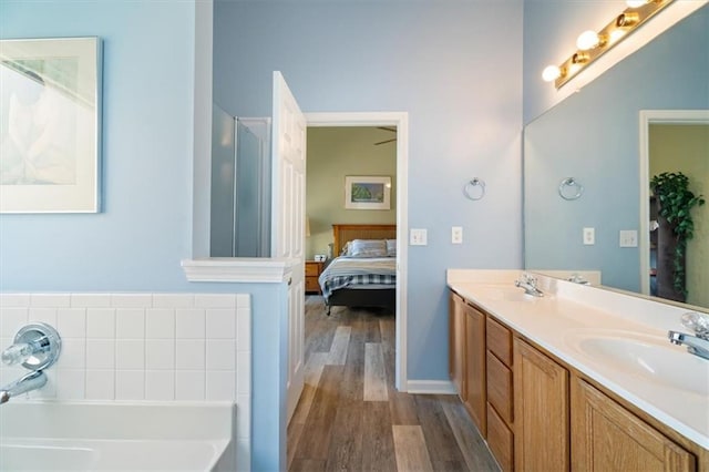 ensuite bathroom featuring a garden tub, double vanity, ensuite bathroom, a sink, and wood finished floors