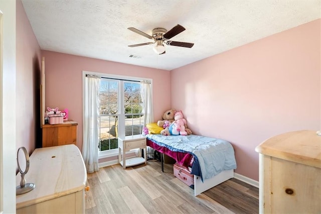 bedroom featuring a ceiling fan, baseboards, light wood-style flooring, and a textured ceiling