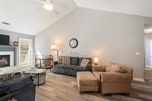 living area featuring visible vents, a fireplace with raised hearth, baseboards, and wood finished floors