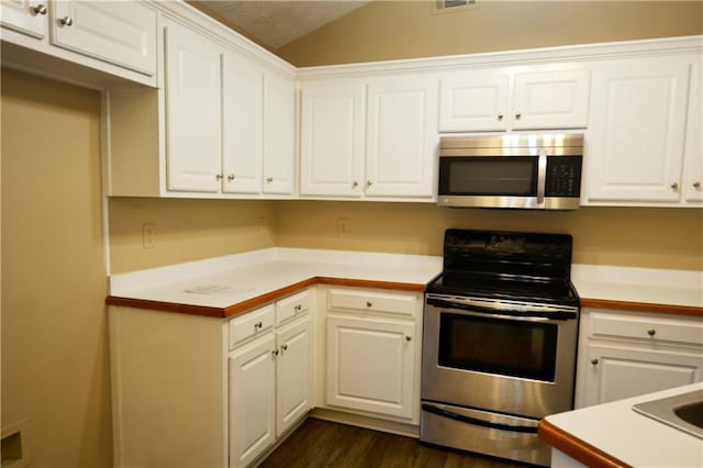 kitchen featuring white cabinetry, lofted ceiling, dark hardwood / wood-style floors, and appliances with stainless steel finishes