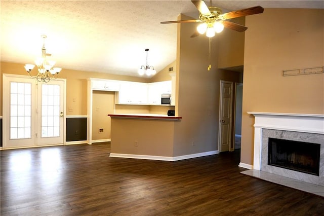 unfurnished living room featuring dark hardwood / wood-style floors, high vaulted ceiling, a premium fireplace, and ceiling fan with notable chandelier