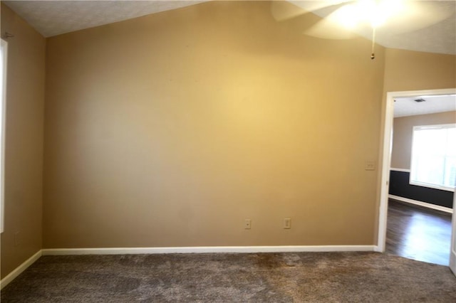 empty room featuring dark carpet and vaulted ceiling