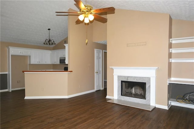 unfurnished living room featuring ceiling fan with notable chandelier, high vaulted ceiling, dark hardwood / wood-style flooring, a high end fireplace, and a textured ceiling