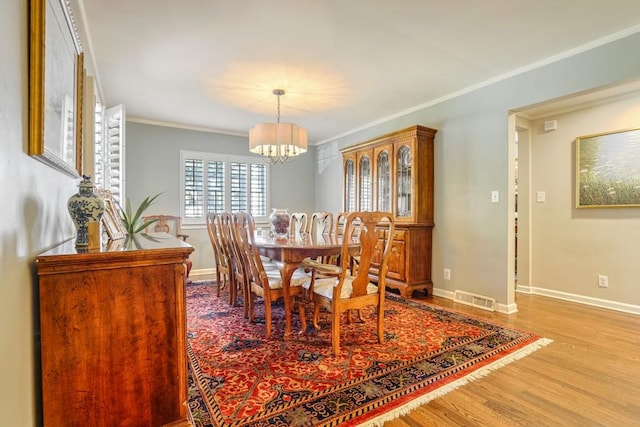 2195 Edison Ave NE, Atlanta, GA 30305 - dining area featuring wood finished floors, crown molding, visible vents, baseboards, and a chandelier