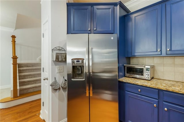 kitchen with blue cabinets, light wood-style flooring, tasteful backsplash, stainless steel fridge, and a toaster