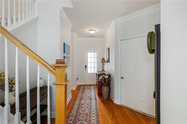 entrance foyer featuring baseboards, wood finished floors, stairs, and crown molding