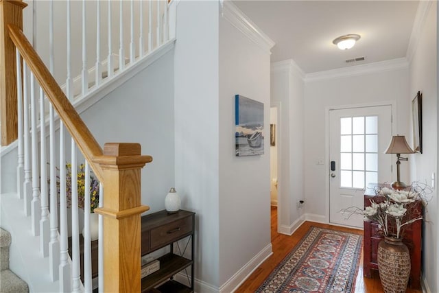 entryway featuring visible vents, wood finished floors, stairway, crown molding, and baseboards