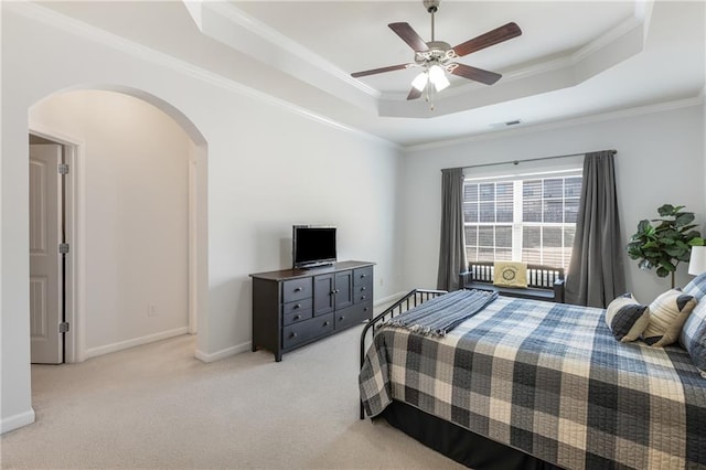 bedroom featuring baseboards, a tray ceiling, arched walkways, crown molding, and light colored carpet