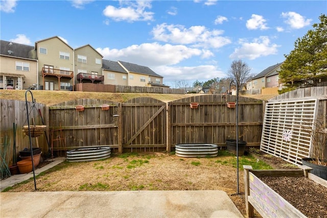 view of yard featuring a residential view, a fenced backyard, and a gate