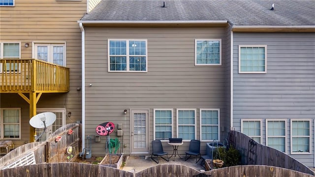 back of property featuring a shingled roof, a patio, and fence