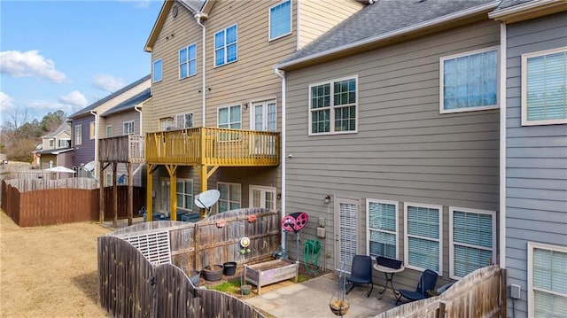 rear view of property featuring a patio, roof with shingles, and fence