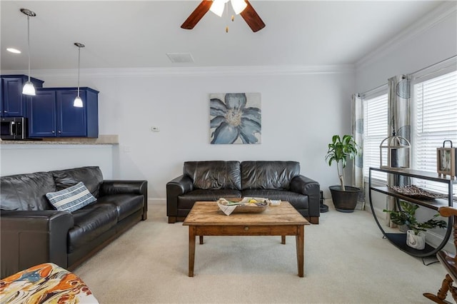 living room featuring a ceiling fan, visible vents, baseboards, light carpet, and crown molding