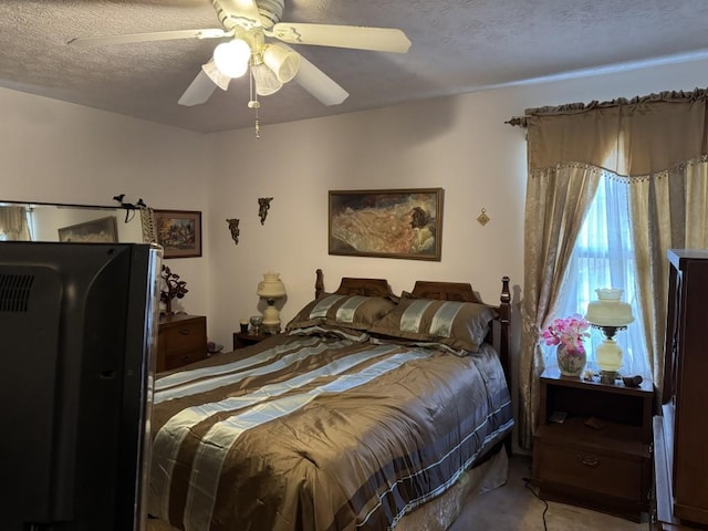 bedroom with ceiling fan, light colored carpet, a textured ceiling, and black fridge