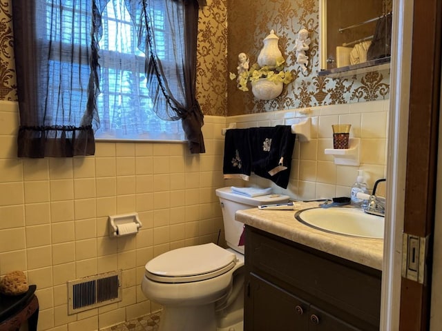 bathroom with toilet, vanity, and tile walls