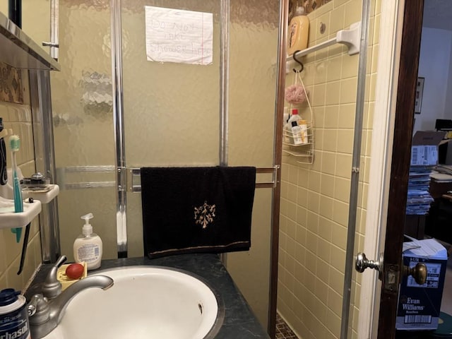 bathroom with a shower with shower door and sink