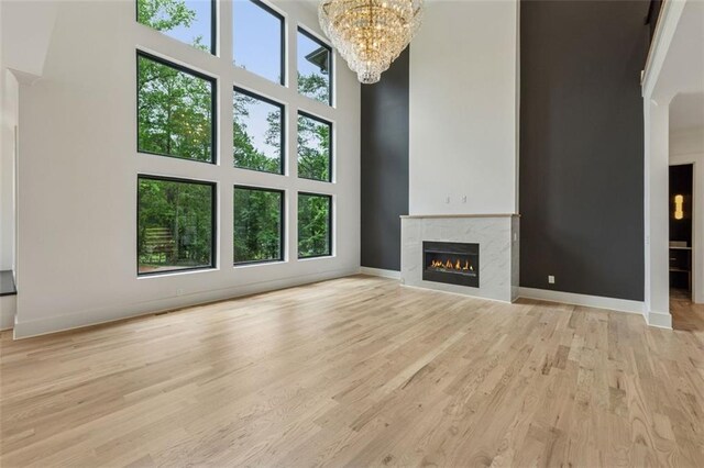 2797 Benson Dr, Marietta, GA 30062 - unfurnished living room with a premium fireplace, a chandelier, light wood finished floors, baseboards, and a towering ceiling