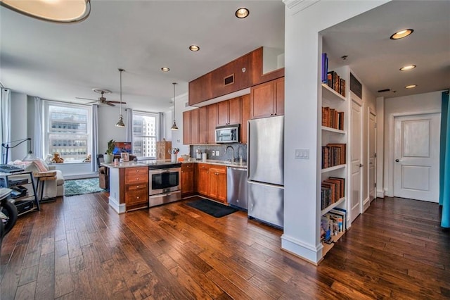 kitchen featuring brown cabinetry, appliances with stainless steel finishes, open floor plan, dark wood-type flooring, and light countertops