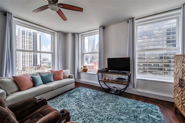 living room featuring recessed lighting, a city view, a ceiling fan, baseboards, and dark wood finished floors