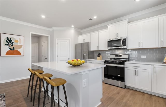 kitchen with white cabinets, backsplash, appliances with stainless steel finishes, and a center island