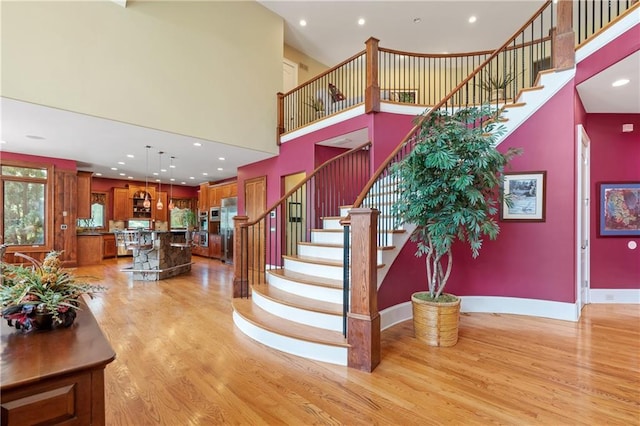 stairway with hardwood / wood-style flooring and a towering ceiling