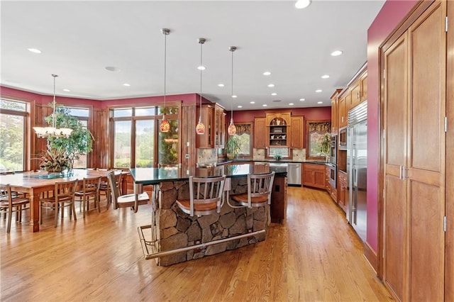 kitchen featuring a breakfast bar, a center island, pendant lighting, light hardwood / wood-style floors, and backsplash