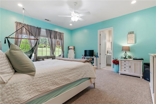 carpeted bedroom with ensuite bathroom and ceiling fan