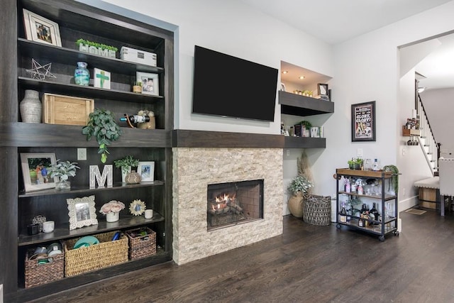 living room featuring dark hardwood / wood-style floors and a stone fireplace