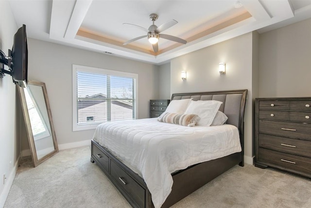 carpeted bedroom with ceiling fan and a tray ceiling