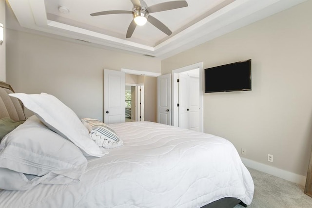 carpeted bedroom featuring ceiling fan and a raised ceiling