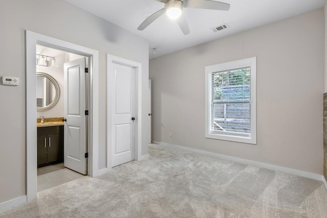 unfurnished bedroom featuring ceiling fan, light carpet, and connected bathroom