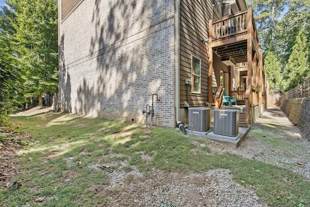 view of side of property with a balcony, a lawn, and central air condition unit