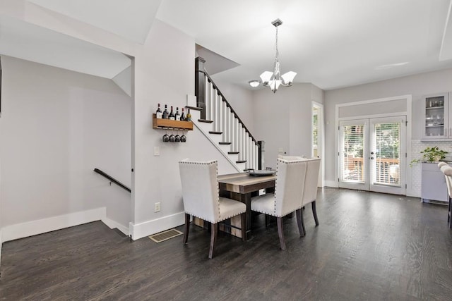 dining room with dark hardwood / wood-style floors, french doors, and an inviting chandelier