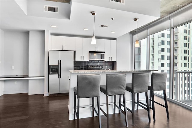 44 Peachtree Pl NE Unit 1929, Atlanta, GA 30309 - kitchen featuring appliances with stainless steel finishes, dark wood finished floors, white cabinets, a breakfast bar area, and recessed lighting