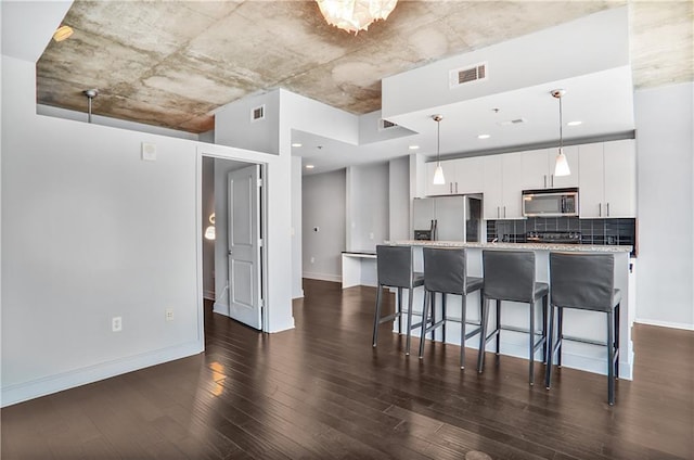 44 Peachtree Pl NE Unit 1929, Atlanta, GA 30309 - kitchen featuring appliances with stainless steel finishes, a breakfast bar area, dark wood finished floors, white cabinetry, and a center island with sink