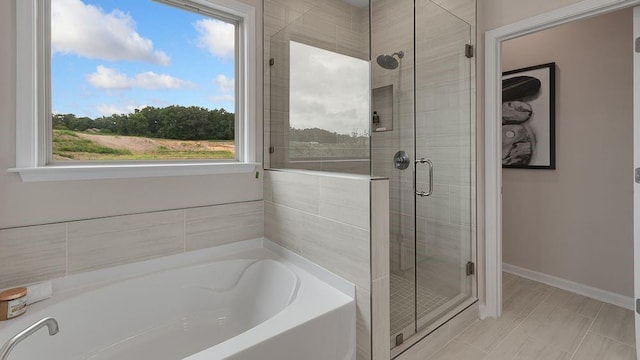 bathroom with a garden tub, a stall shower, and baseboards
