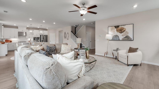 living room with light wood-style floors, recessed lighting, a ceiling fan, and baseboards