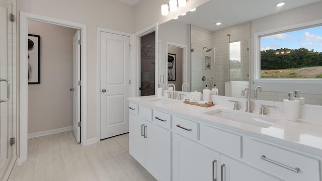 bathroom featuring double vanity, a walk in closet, a stall shower, and a sink