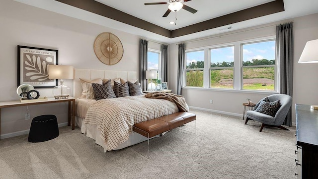 carpeted bedroom with baseboards, a ceiling fan, and a tray ceiling