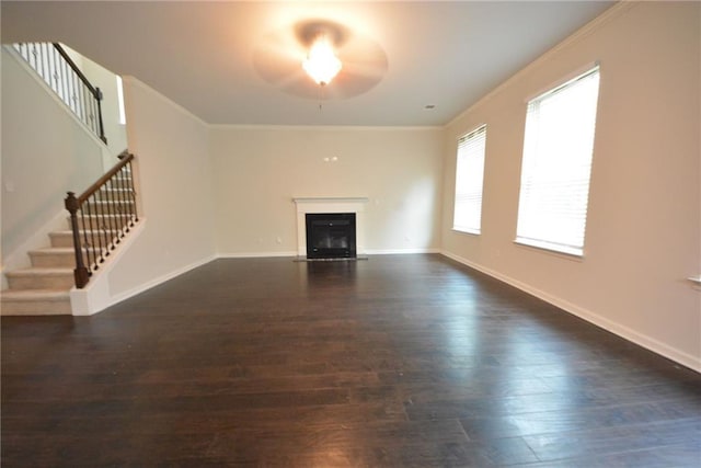 unfurnished living room with dark wood-type flooring, stairway, a ceiling fan, a fireplace, and ornamental molding