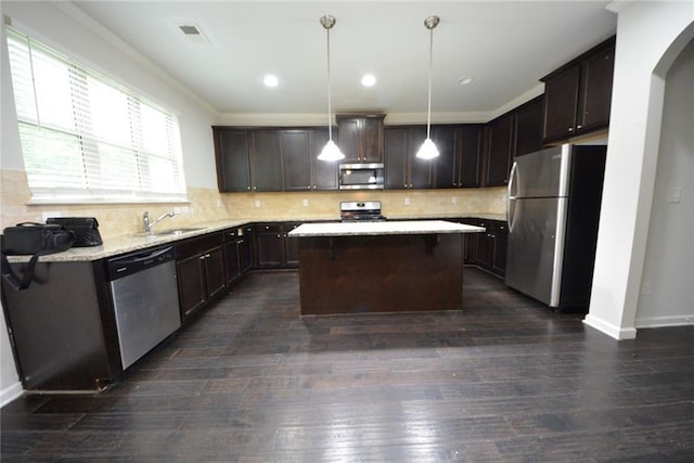 kitchen featuring stainless steel appliances, dark brown cabinetry, a sink, a center island, and crown molding