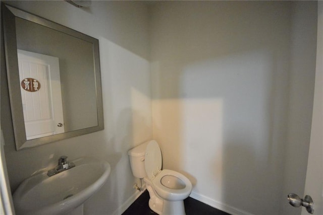 bathroom featuring baseboards, a sink, and toilet