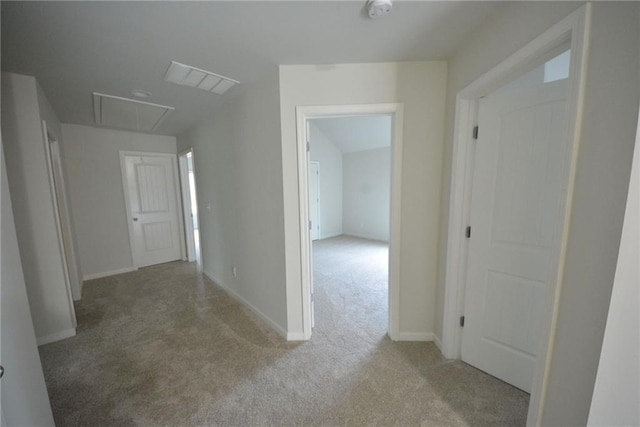 corridor featuring attic access, carpet, and baseboards